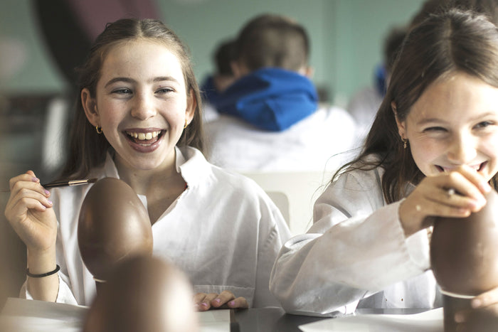 Two young girls smiling and decorating chocolate eggs